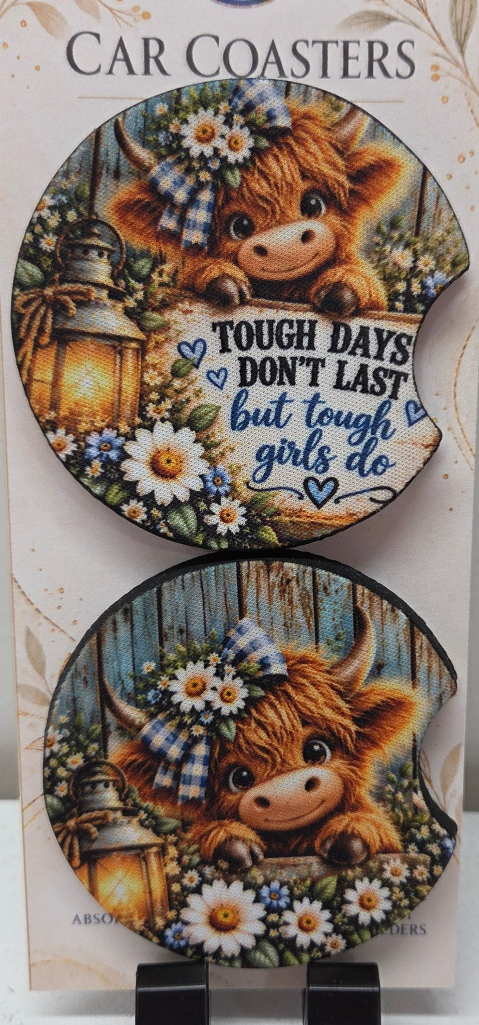 Actual photo of two Highland cow neoprene car coasters with finger notches, one with Tough Days Don't Last but Tough Girls Do lettering
