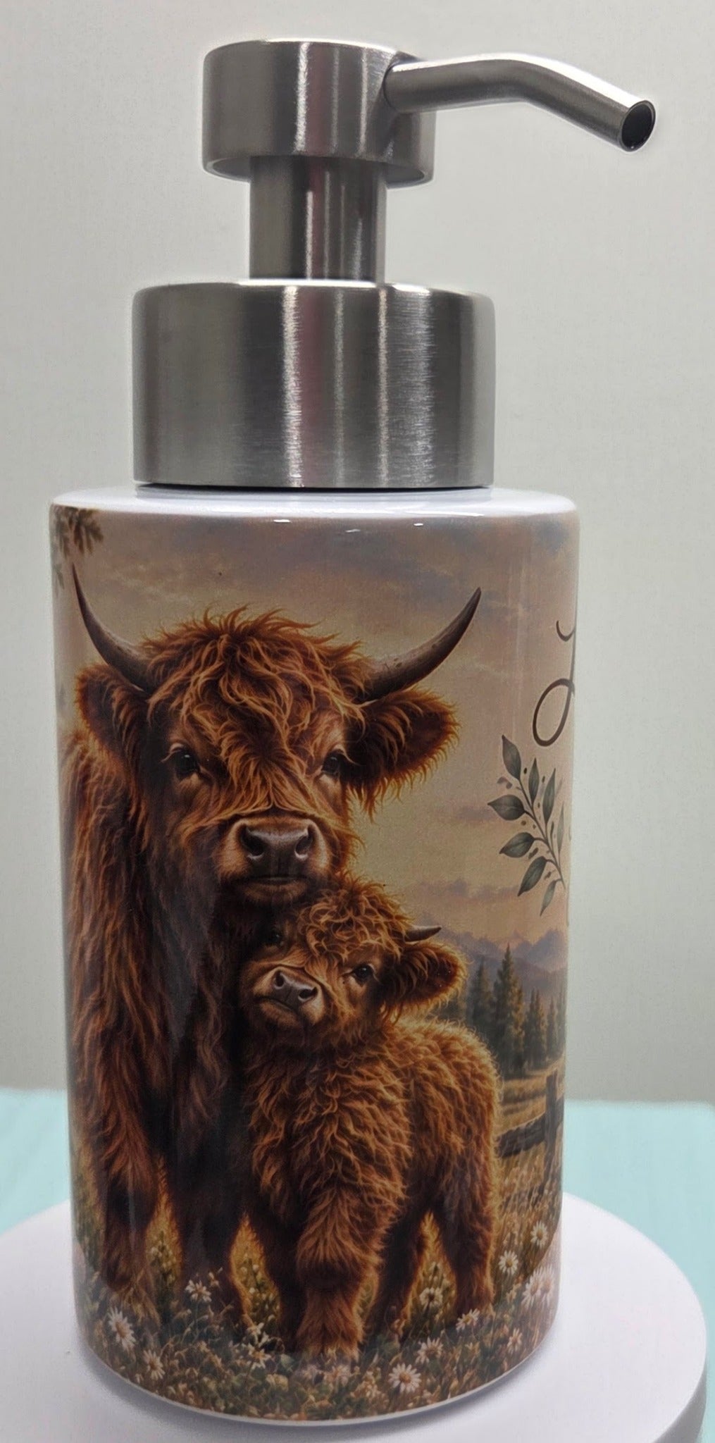 Actual soap dispenser showing brown Highland cow and calf in wildflower meadow